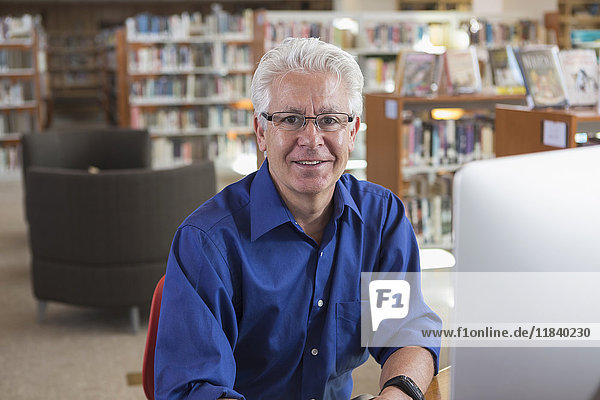 Smiling Hispanic man using computer in library
