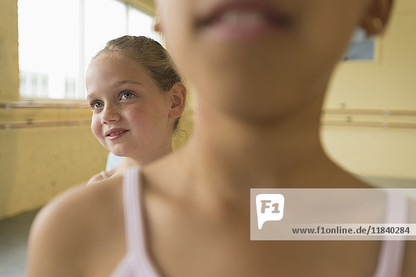 Girl peeking over shoulder of girl in ballet studio