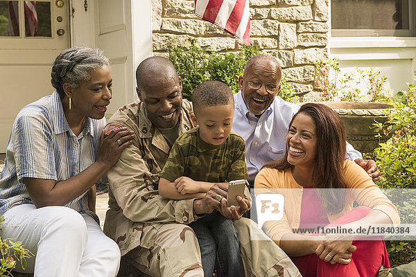 Soldat und Mehrgenerationenfamilie mit Blick auf das Mobiltelefon