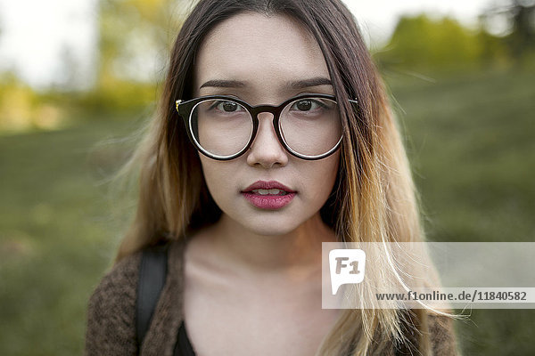 Asian teenage girl wearing eyeglasses in field