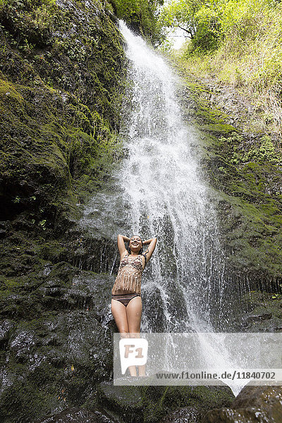 Kaukasische Frau steht auf einem Felsen in der Nähe eines Wasserfalls