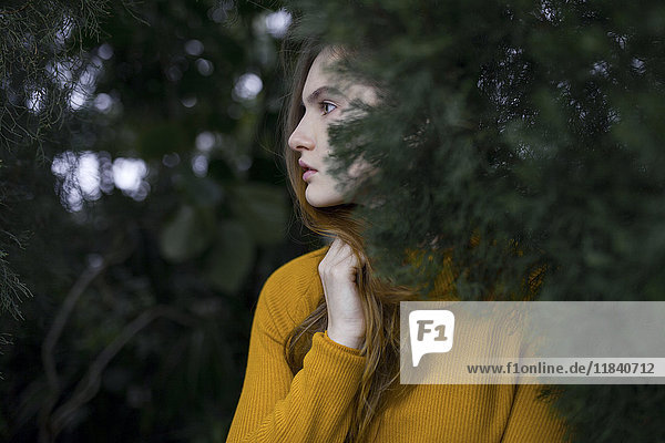 Pensive Caucasian woman standing near tree branch