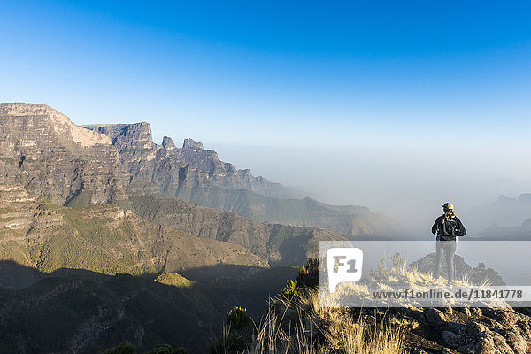Frau genießt die frühe Morgensonne auf den Klippen  Simien Mountains National Park  UNESCO Weltkulturerbe  Debarq  Äthiopien  Afrika