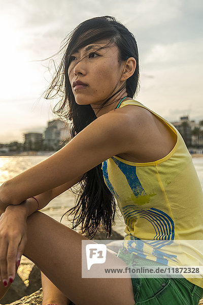 Porträt einer chinesischen jungen Frau  die am Strand von Sitges sitzt; Sitges  Provinz Barcelona  Spanien