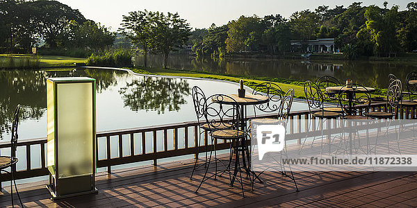 Eine Terrasse mit Stühlen und Tischen mit Blick auf einen ruhigen Fluss; Chiang Rai  Thailand'.