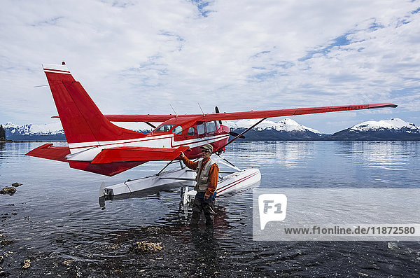 Mann steht neben einem Cessna 206 Wasserflugzeug in der Hobo Bay  Port Wells  Prince William Sound  Süd-Zentral-Alaska  USA