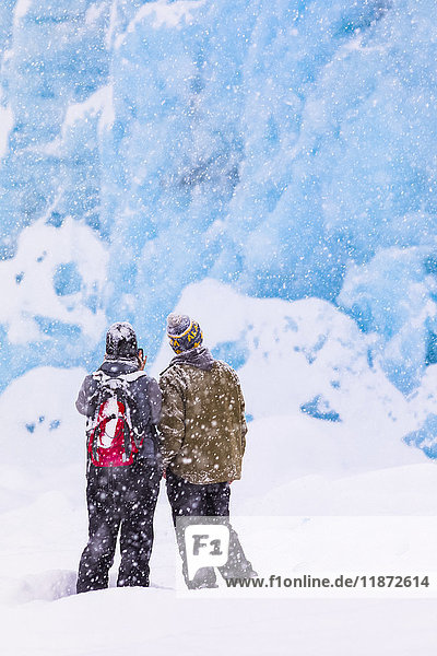 Ein Paar überquert den Portage Lake bei starkem Schneefall im Winter mit Schneeschuhen  um den Endpunkt des Portage Glacier zu sehen  Süd-Zentral-Alaska  USA