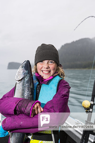 Junges Mädchen umarmt einen Silberlachs auf einem Fischerboot  Seward  Süd-Zentral-Alaska  USA