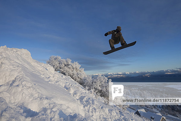 Snowboarder beim Springen mit der Kachemak Bay im Hintergrund  Homer  Süd-Zentral-Alaska  USA