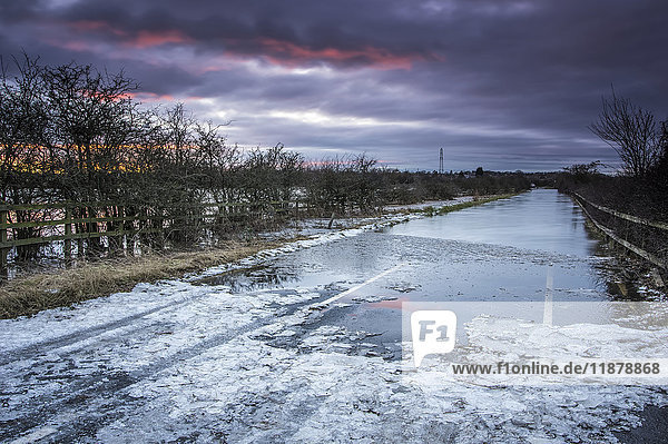 'Flooded road with snow and water in winter at sunset; South Tyneside  Tyne and Wear  England'