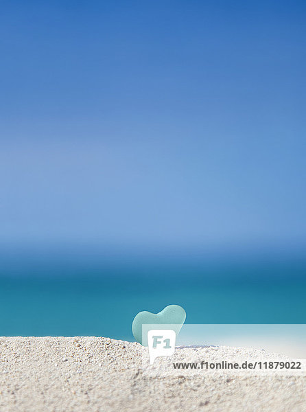Ein türkisfarbenes  herzförmiges Seeglas im Sand am Strand; Honolulu  Oahu Hawaii  Vereinigte Staaten von Amerika'.