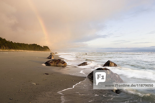 Ein Regenbogen leuchtet in Gewitterwolken über einem Strand und einer Küste; Alaska  Vereinigte Staaten von Amerika'.