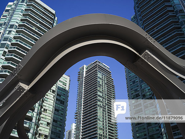 'A steel arch in the foreground with residential skyscrapers against a blue sky in the background; Toronto  Ontario  Canada'