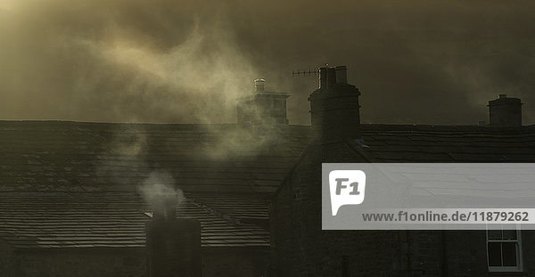 'Smoke from chimneys on a rooftop floats into the air; Reeth  Yorkshire  England'