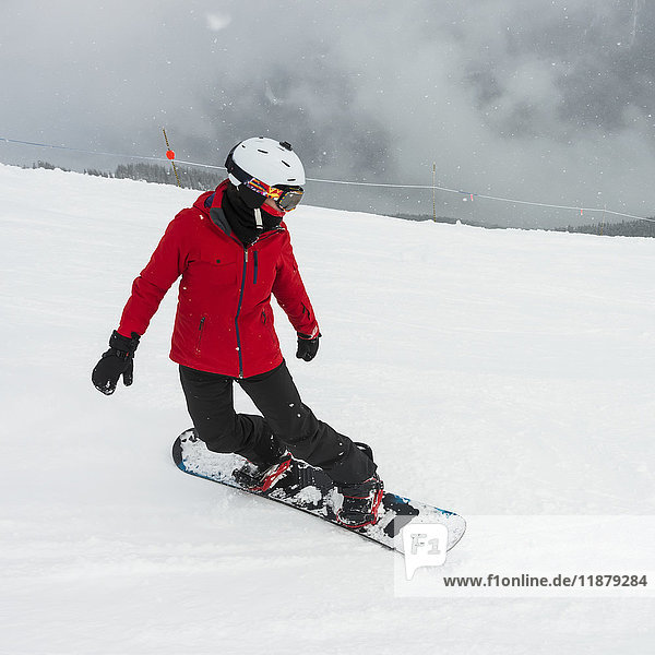 'A snowboarder in a red jacket snowboarding in the Canadian Rockies; Whistler  British Columbia  Canada'