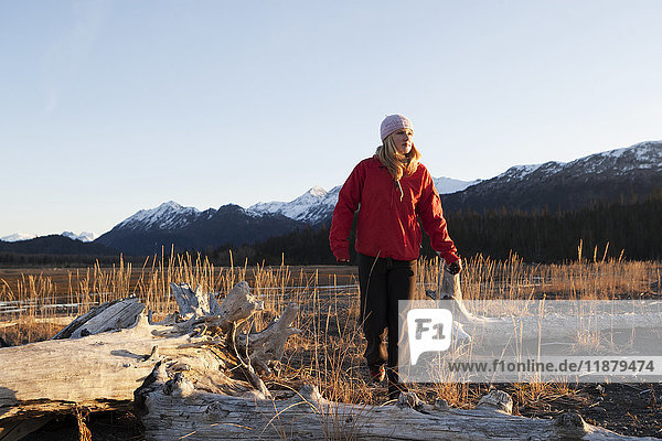 Eine junge Frau läuft an Treibholz im Kachemak Bay State Park vorbei; Alaska  Vereinigte Staaten von Amerika'.