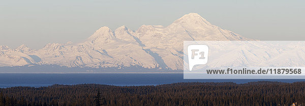 Schneebedeckte Berge in der Ferne mit Meer und Wald im Vordergrund; Alaska  Vereinigte Staaten von Amerika'.