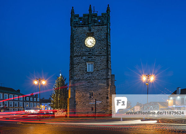'The clock in a tower and lamp posts glow with illumination at dusk  with light trails on the street; Richmond  Yorkshire  England'