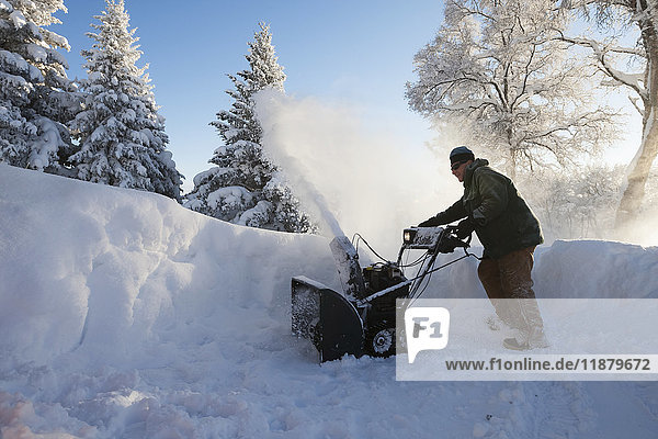 Ein Mann benutzt eine Schneefräse im tiefen Schnee; Homer  Alaska  Vereinigte Staaten von Amerika'.