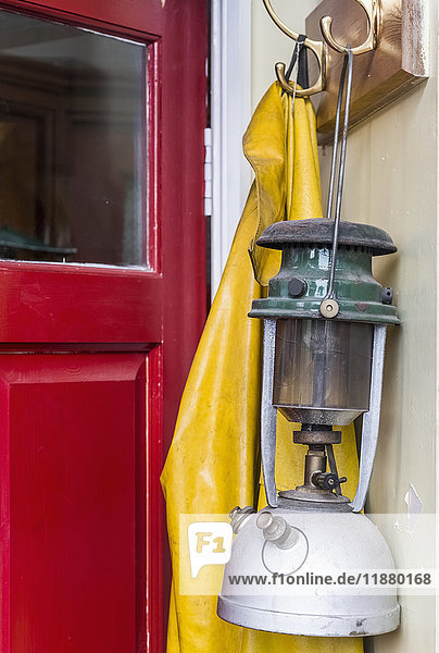 'A lantern and yellow rain jacket hang beside a red door; Yorkshire  England'