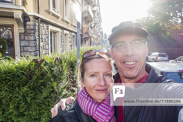 'A couple takes a self-portrait beside a street and building; Lausanne  Switzerland'