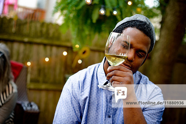 Mann auf Gartenparty  hält Weinglas  inspiziert Wein