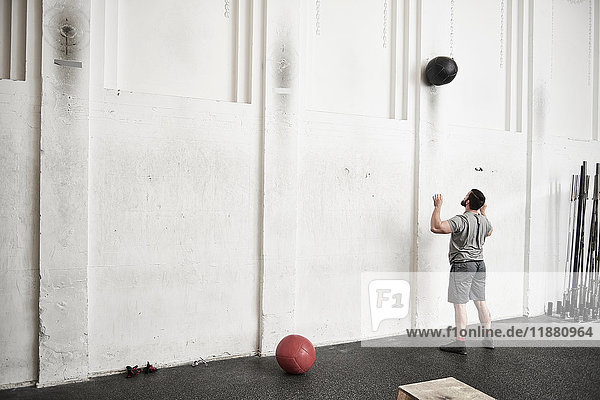 Mann wirft Fitnessball in Cross-Trainingshalle gegen Wand