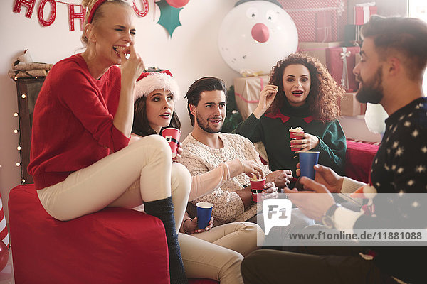 Young women and men eating popcorn on sofa at christmas party