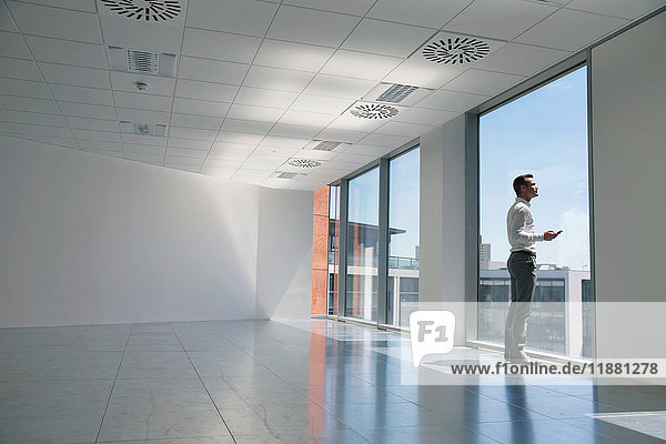 Geschäftsmann schaut aus dem Fenster  in leeren Büroräumen