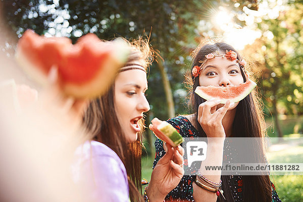 Young boho women making smiley face with melon slice at festival