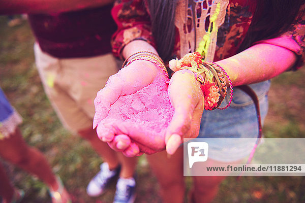 Pink chalk cupped in young woman's hands at festival