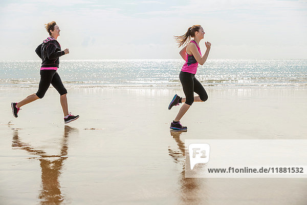 Mutter und Tochter laufen am Strand  Folkestone  UK