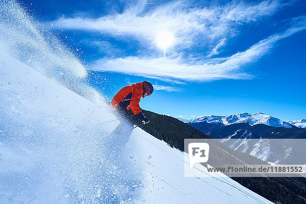 Mann fährt auf Skiern einen tief verschneiten Berghang hinunter  Aspen  Colorado  USA