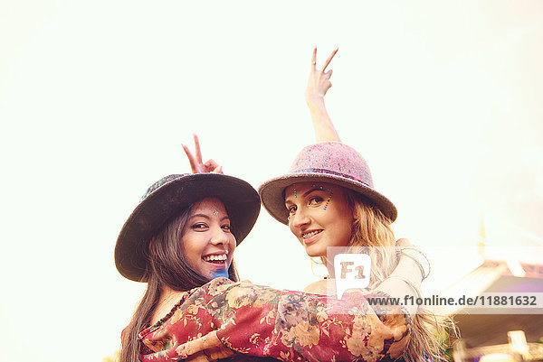 Portrait of two young female friends making peace sign at festival