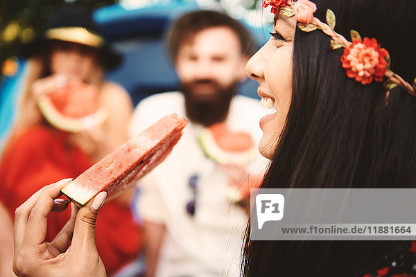 Junge Boho-Frau isst Melonenscheibe beim Festival