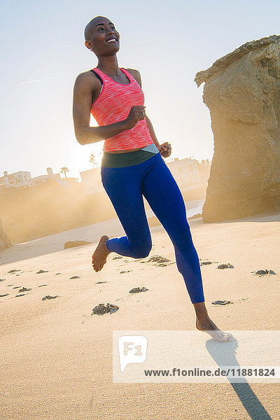 Young woman exercising  running  on beach  low angle view