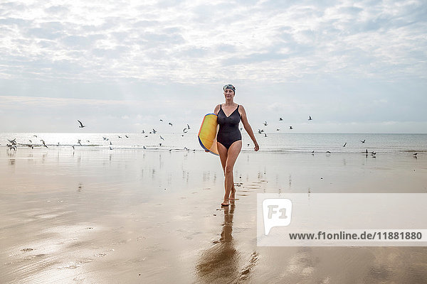 Frau trägt Surfbrett am Strand  Folkestone  UK