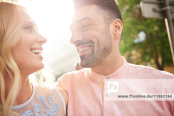 Portrait of couple in sunlight face to face smiling