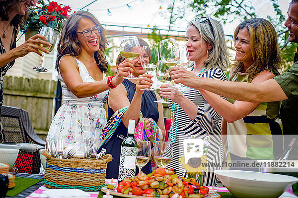 Personengruppe bei Gartenparty  hält Weingläser  spricht einen Toast aus