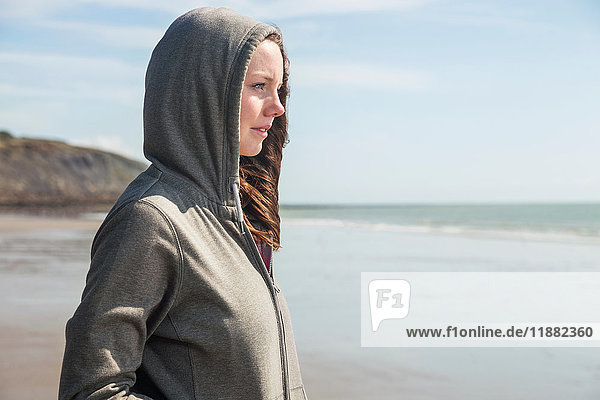Junge Frau am Strand in Kapuzenjacke  Folkestone  UK
