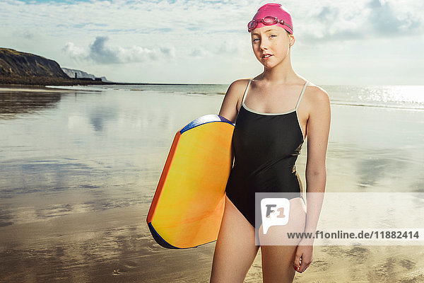 Porträt eines selbstbewussten jungen Bodyboarder im Badeanzug am Strand