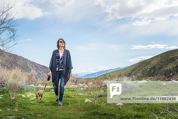 Mature woman walking dog in valley landscape