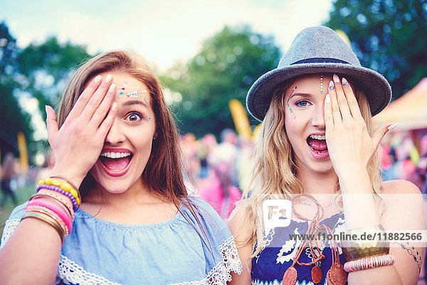 Porträt von zwei jungen Freundinnen  die auf dem Festival ein Auge zudecken