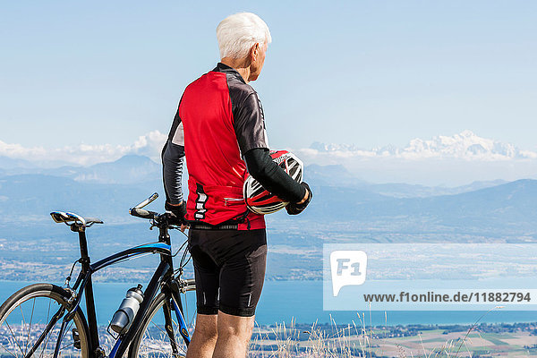 Älterer Mann in Fahrradkleidung  auf dem Hügel stehend  neben dem Fahrrad  Blick auf Aussicht  Genf  Schweiz  Europa