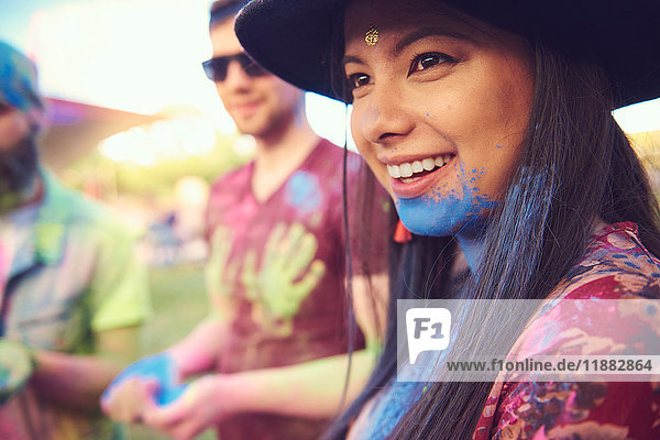 Junge Boho-Frau mit blauem Kreidepulver am Kinn beim Festival