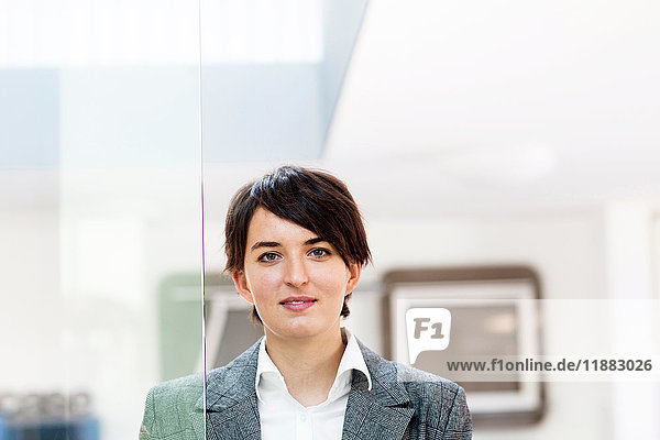 Portrait of young female sales manager by glass door in office furniture store