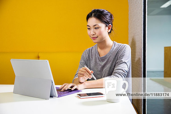 Female digital designer at office desk using laptop