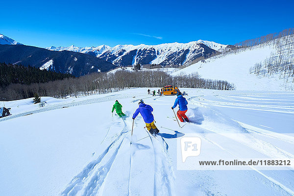 Rear view of men skiing down snow covered ski slope  Aspen  Colorado  USA