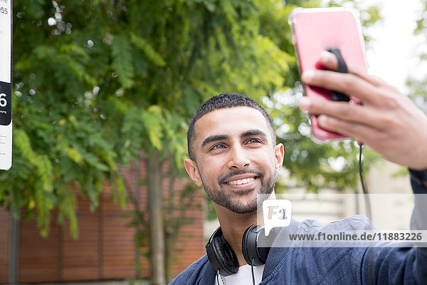 Young man outdoors  taking selfie using smartphone