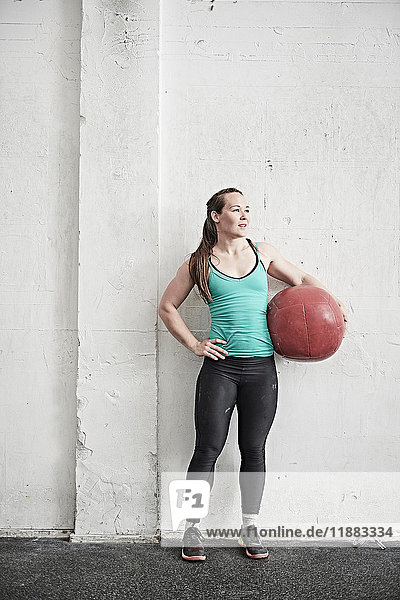 Woman carrying fitness ball in cross training gym